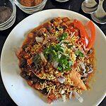 Samosa Chaat is mashed samosa topped with peas or chole masala and topped with tangy chutneys, sev, onion and tomatoes if you wish.