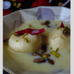 Sweet rasgulla dipped in thickened milk and garnished with rose, pistachios and saffron