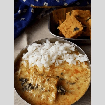 a small plate of white steamed rice and Pithore ki Sabzi