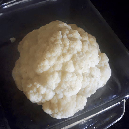 Boiled head of cauliflower set in an oven-proof dish for Gobi Musallam
