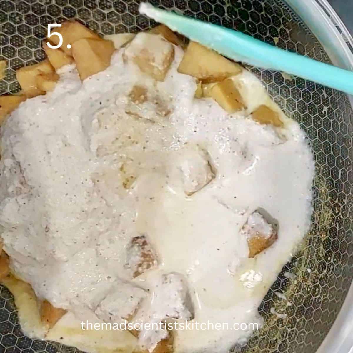 Adding the ground coconut mix to the cooked yam.